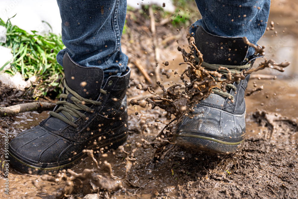 A man in jeans and boots walks through the swamp in rainy weather. A man in jeans and boots walks through the swamp in rainy weather.