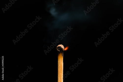Igniting match on a black background, macro photography. Newly lit match with smoke on a black background. Concept of beginning, leadership, strengthening the spirit