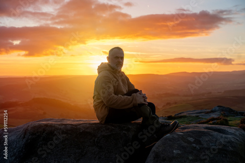 Bearded Man reaching the destination and on the top of mountain at sunrise or sunset on cold  day Travel Lifestyle concept The national park Pick District in England