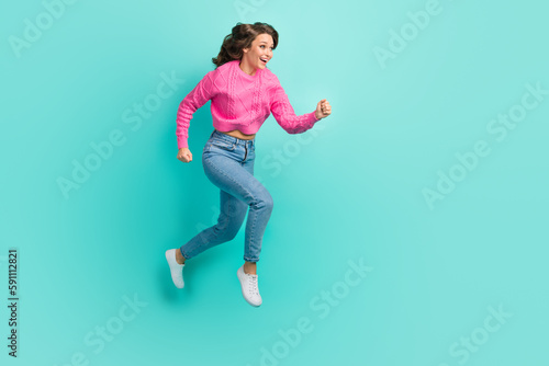 Full length photo of adorable excited lady dressed knitted pullover running fast jumping empty space isolated teal color background