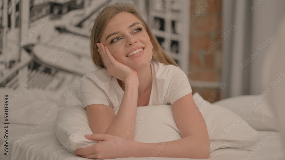 Pensive Young Woman Lying on Stomach in Bed Pensive Young Woman Lying on Stomach in Bed