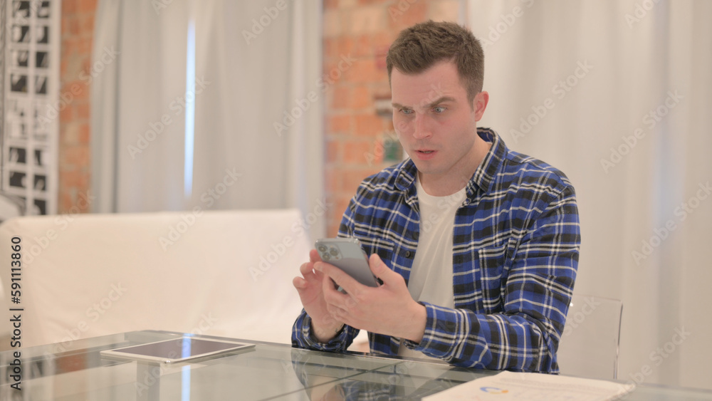 Upset Young Casual Man get Shocked on Smartphone