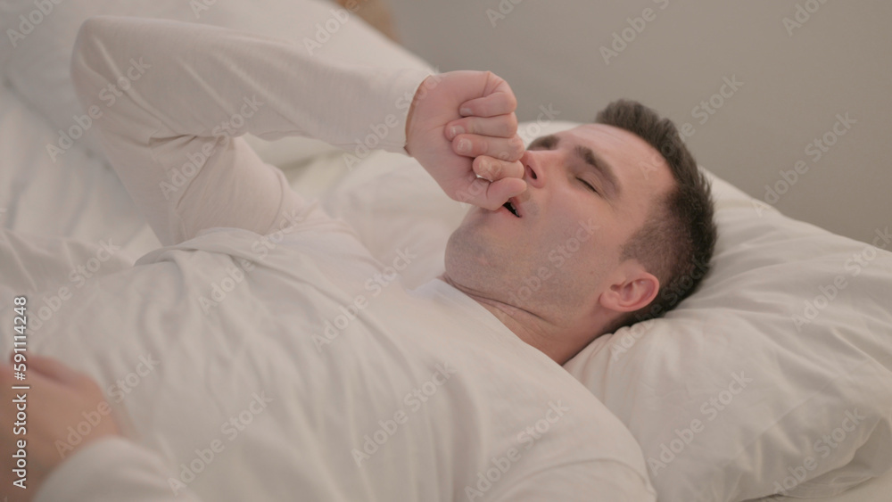Sick Young Man Coughing while Lying in Bed Sick Young Man Coughing while Lying in Bed