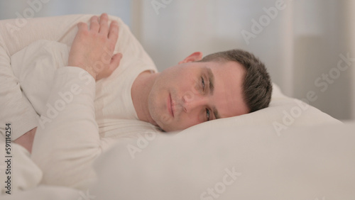 Pensive Young Man Sleeping in Bed on Side