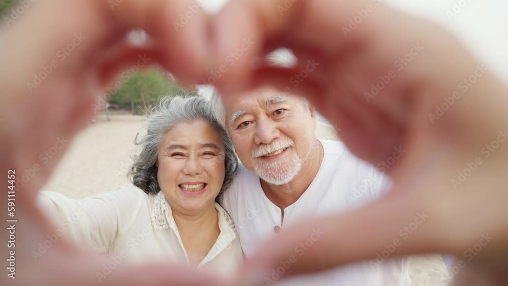 Portrait of Happy Asian family senior couple with gray hair taking picture together at tropical beach at summer sunset. Retired elderly people enjoy outdoor lifestyle travel ocean on holiday vacation. Portrait of Happy Asian family senior couple with gray hair taking picture together at tropical beach at summer sunset. Retired elderly people enjoy outdoor lifestyle travel ocean on holiday vacation.