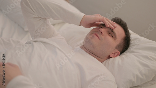 Young Man with Headache Lying in Bed 