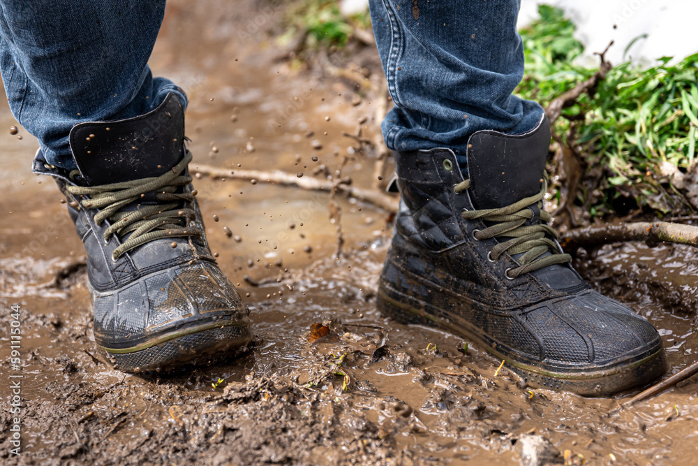 A man in jeans and boots walks through the swamp in rainy weather. A man in jeans and boots walks through the swamp in rainy weather.