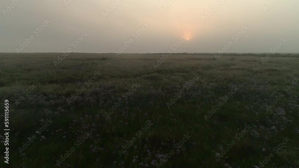 Low Aerial Drone Shot Flying Over Salt Marsh at Foggy Low Light Sunrise North Norfolk UK East Coast