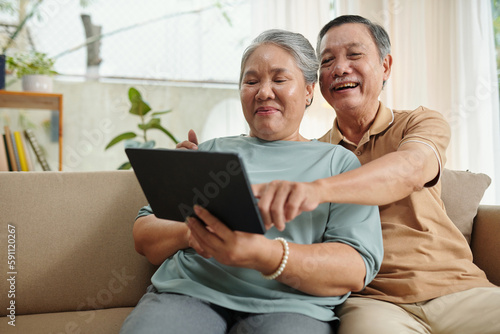 Happy aged couple waching comedy movie on digital tablet
