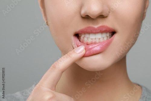 Woman showing healthy gums on grey background, closeup photo