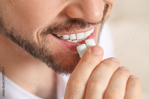 Fototapet Man putting chewing gums into mouth on blurred background, closeup