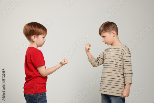 Boys with clenched fists on light grey background. Children's bullying
