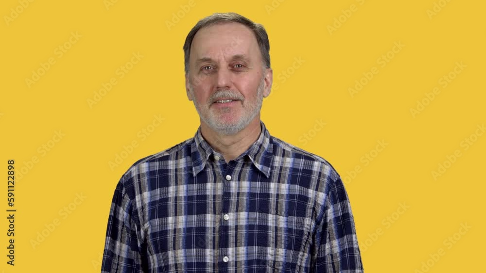 Portrait of confident aged senior man in checkered shirt. Isolated in orange background. Portrait of confident aged senior man in checkered shirt. Isolated in orange background.