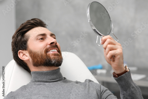 Man looking at his new dental implants in mirror indoors photo