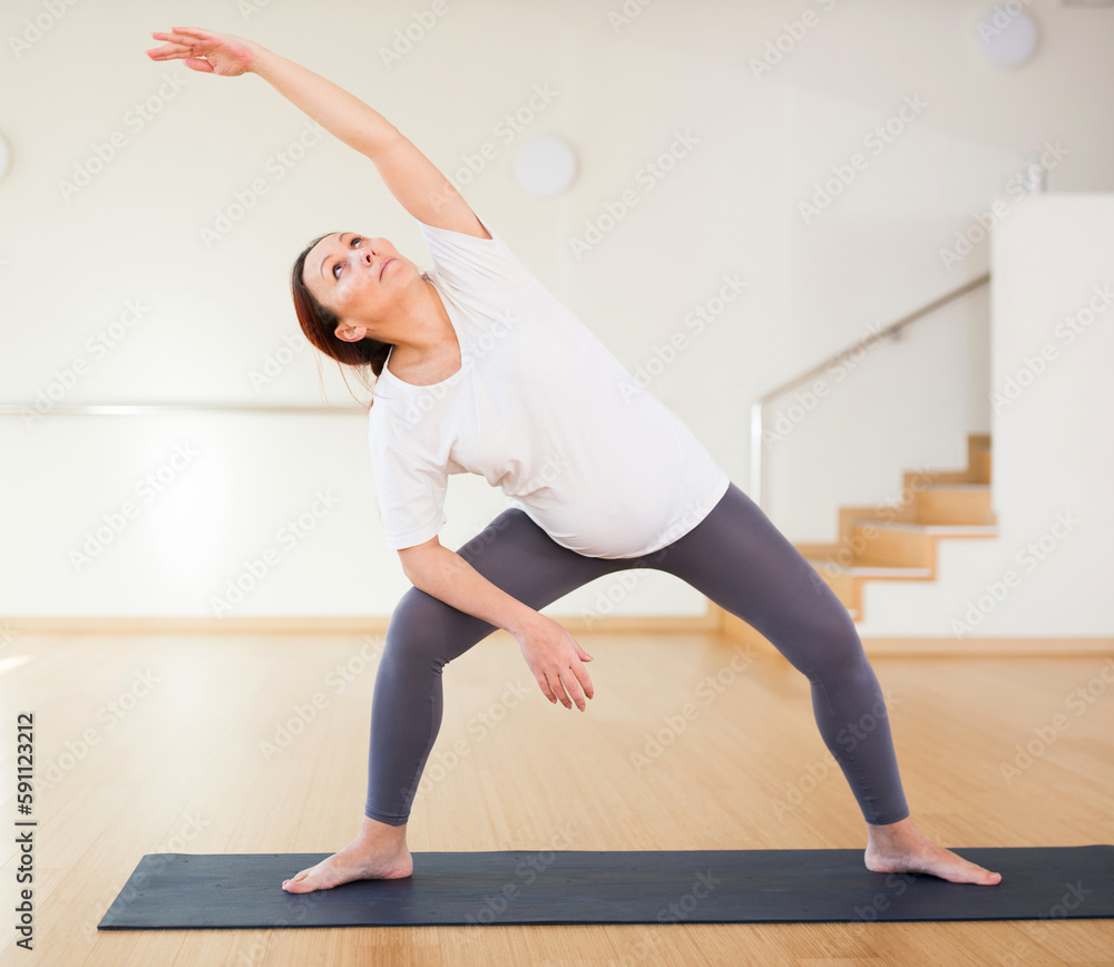 Pregnant woman is engaged in yoga. Extended Side Angle Pose or Utthita Parsvakonasana