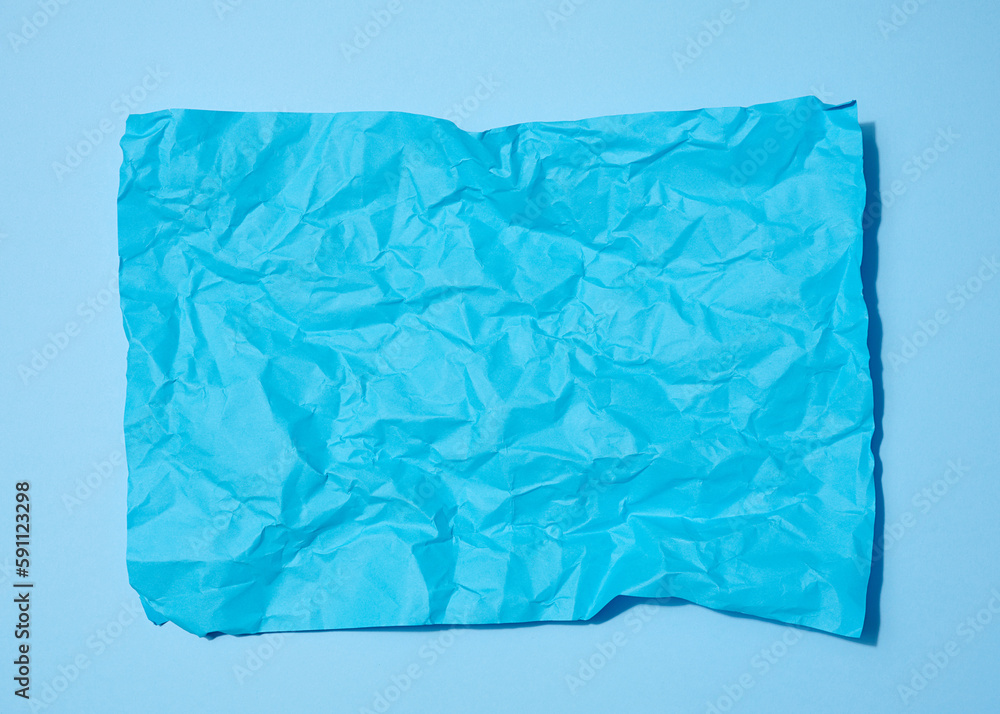 Crumpled rectangular sheet of blue paper on a blue background, top view. Place for inscription Crumpled rectangular sheet of blue paper on a blue background, top view. Place for inscription