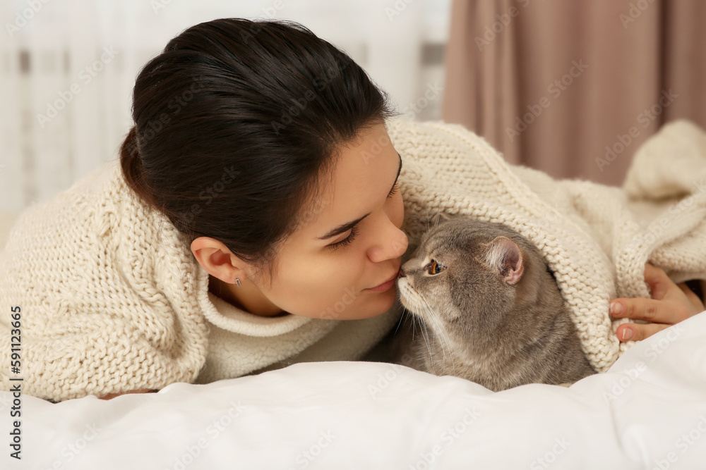 Young woman kissing her adorable cat at home Young woman kissing her adorable cat at home