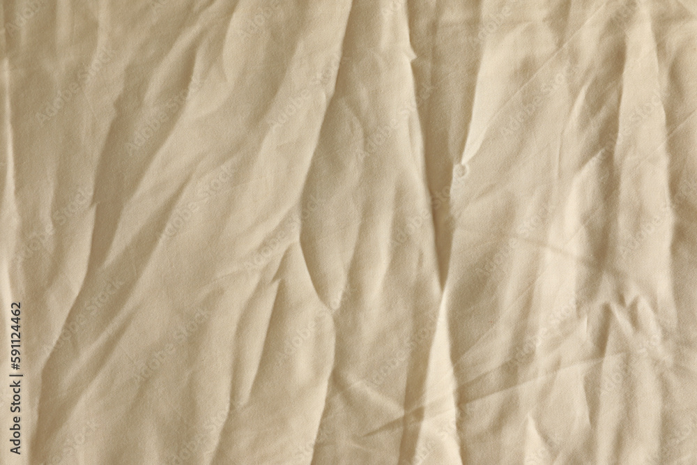 Obraz premium Crumpled beige fabric as background, top view