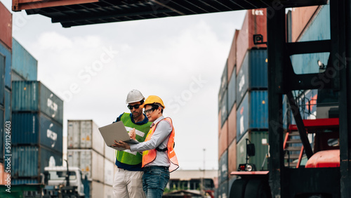 Team Engineer and worker wear safety uniform check control loading freight cargo container use computer laptop at commercial dock warehouse,transportation import,export logistic industrial service