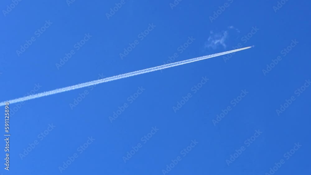 Static shot of a plane flying across the sky leaving white trails in the clear blue skies Static shot of a plane flying across the sky leaving white trails in the clear blue skies