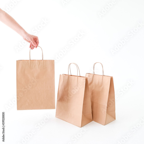 The hand reaches for a craft bag on a white background. Space for text and logo. The concept of packaging, delivery, shopping, food.