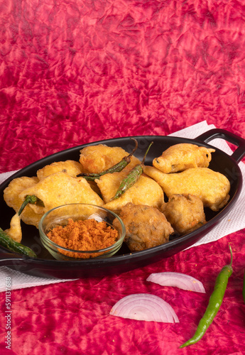 Indian Tea time snacks in group includes Veg Samosa, Kachori/kachaudi, aloo bonda, khaman dhokla, bread, onion,chilli and moong pakora/pakoda/bhaji/bhajji/Bhajiya/bajji with sauces, selective focus photo