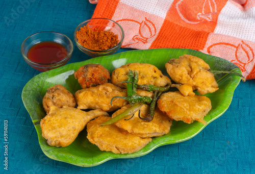 Indian Tea time snacks in group includes Veg Samosa, Kachori/kachaudi, aloo bonda, khaman dhokla, bread, onion,chilli and moong pakora/pakoda/bhaji/bhajji/Bhajiya/bajji with sauces, selective focus photo