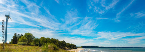 Panrama with a wind turbine in the countryside by the sea. A hopeful eco-friendly backdrop on the theme of generating energy using renewable resources. Narrow web banner template. photo