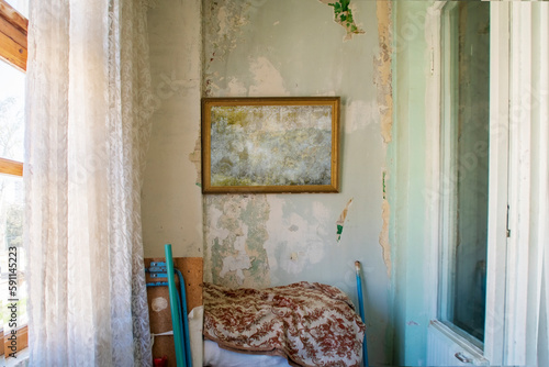 An empty picture frame in an old room with a white shabby wall. Poor housing in Central Asia or Eastern Europe.