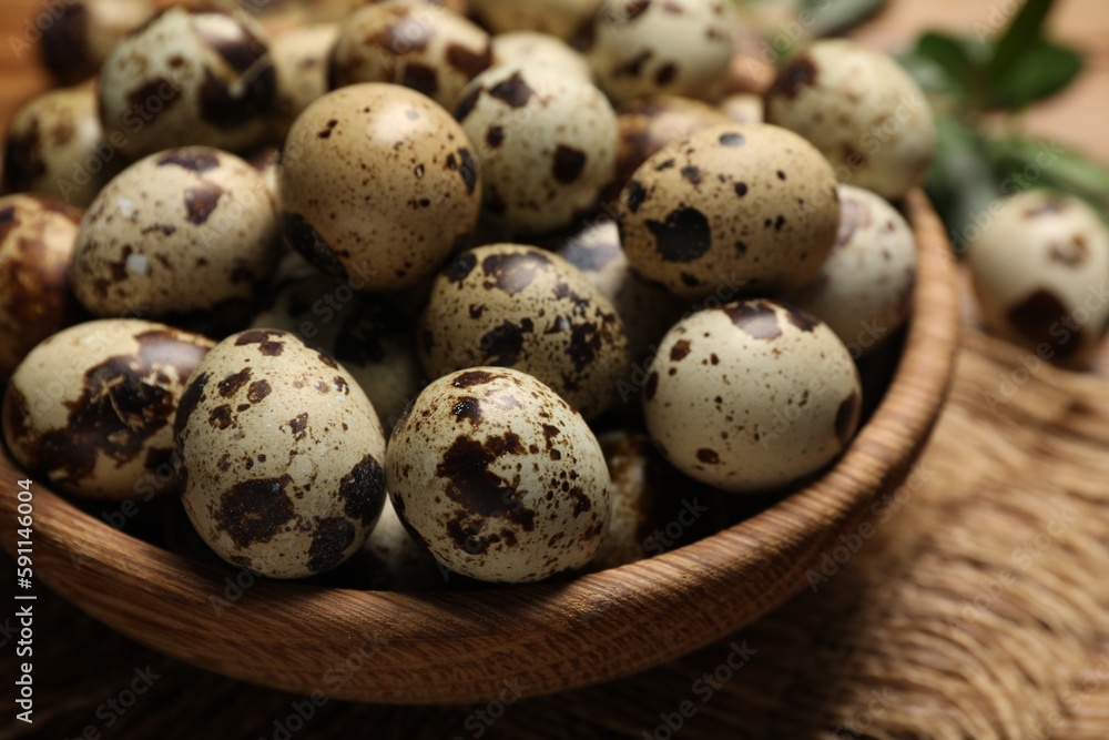 Wooden bowl with quail eggs on table, closeup Wooden bowl with quail eggs on table, closeup