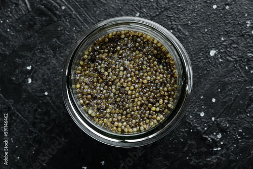 A jar with high-quality black caviar. Luxury food. On a concrete background.