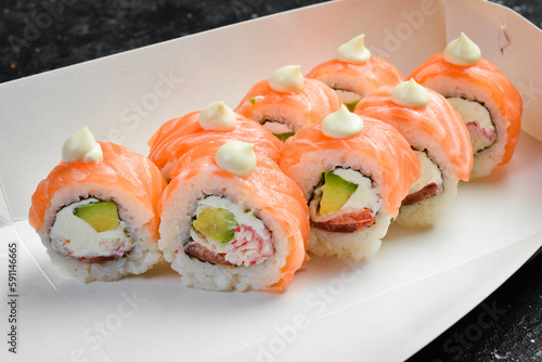 Sushi rolls with cheese and crab and caviar, Japanese food. Delivery. Disposable tableware. On a black stone background.