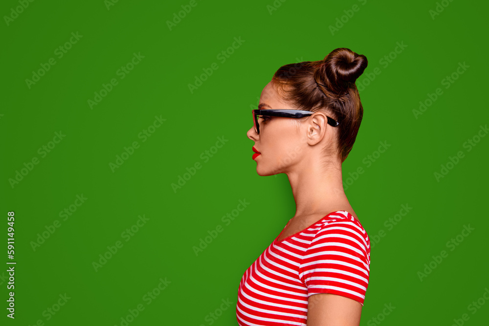 Half-faced side profile view portrait of serious and confident young woman in striped shirt and spectacles isolated on red vivid background with copy space Half-faced side profile view portrait of serious and confident young woman in striped shirt and spectacles isolated on red vivid background with copy space