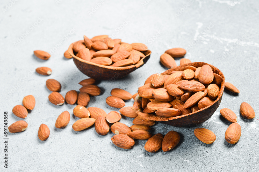 Board with bowl of almonds on a light stone background. Healthy snacks. Nuts Board with bowl of almonds on a light stone background. Healthy snacks. Nuts