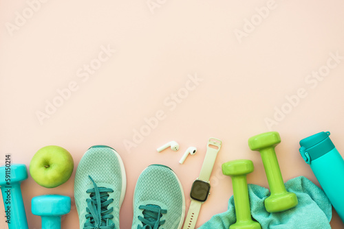 Workout, healthy lifestyle concept. Sneakers, dumbbells, green apple and bottle of water. Flat lay with copy space. © nadianb