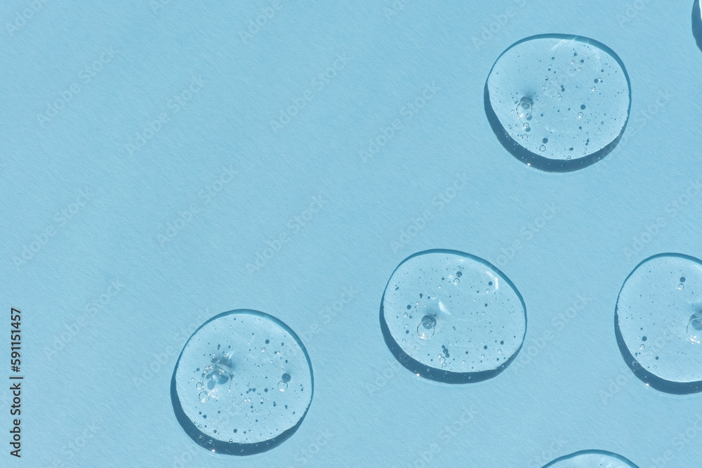 Naklejka premium Drops of serum or hyaluronic acid gel with bubbles on a blue background. Smears of cosmetic skin care products. Wellness and beauty concept