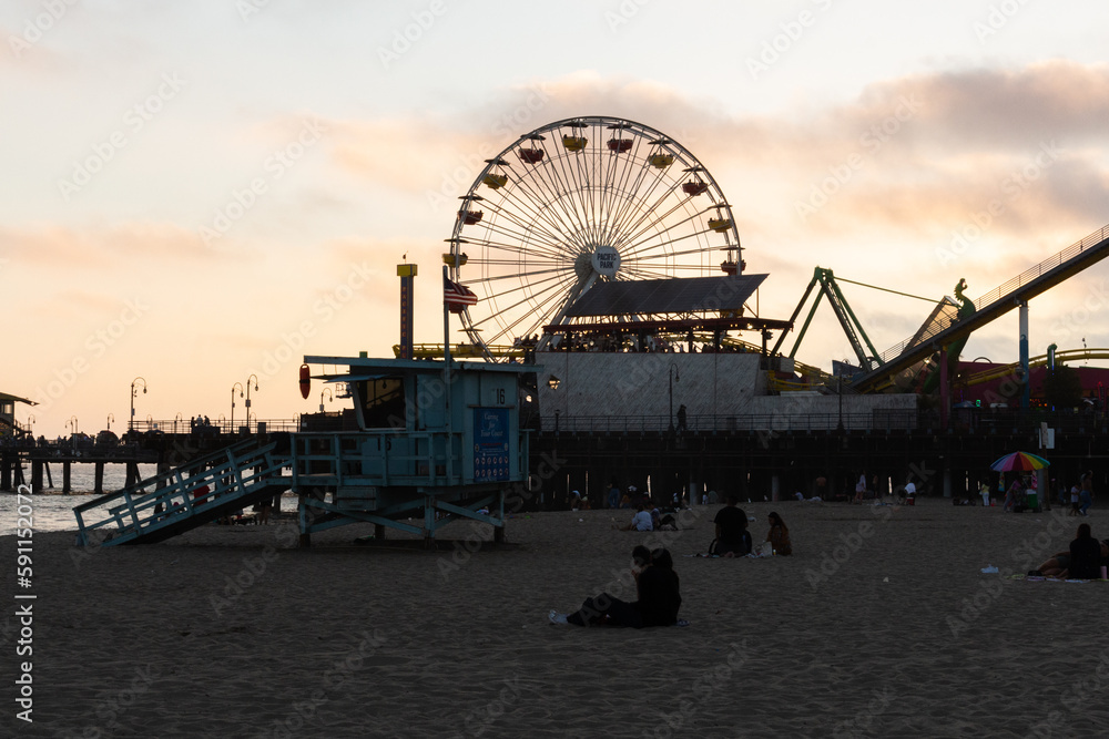 Los Angeles, California, USA, June 21, 2022: View of Santa Monica Beach and the Pier at sunset. Santa Monica Ferris Wheel and Roller-coaster.