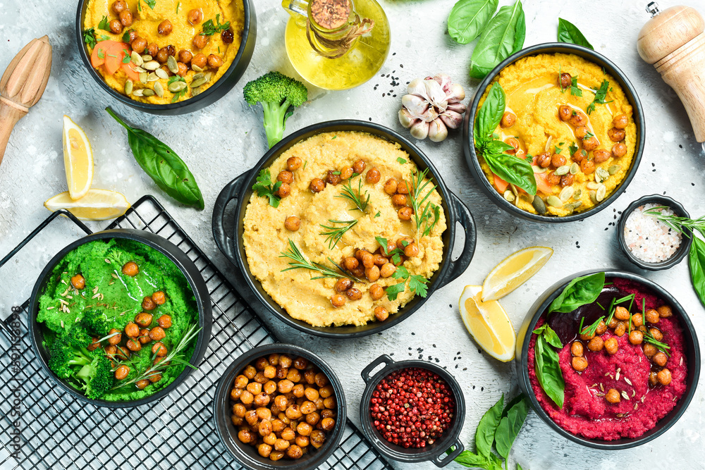 hummus bowls background. Traditional hummus, herb hummus, beetroot hummus. On a concrete gray background. Top view. hummus bowls background. Traditional hummus, herb hummus, beetroot hummus. On a concrete gray background. Top view.