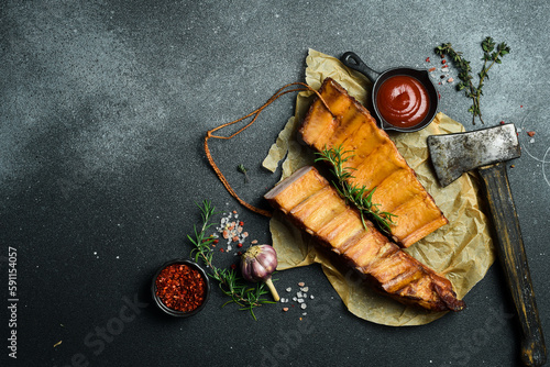 Smoked pork ribs with spices on a stone background. On a black stone background. Free space for the recipe.
