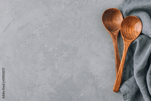 Wooden spoons. Two wooden spoons with napkin on gray concrete stone background, kitchen concept.