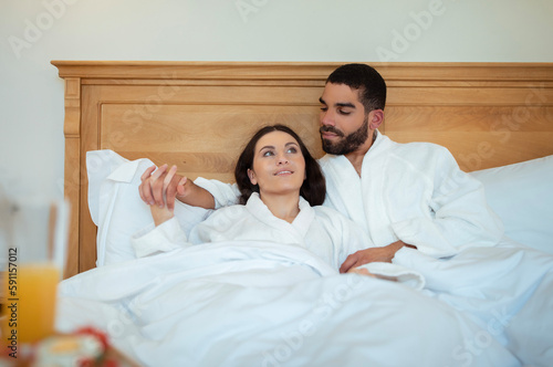 Couple Hugging Lying In Bed In Hotel Room Enjoying Vacation