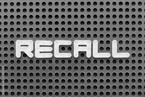 White alphabet letter in word recall on black pegboard background
