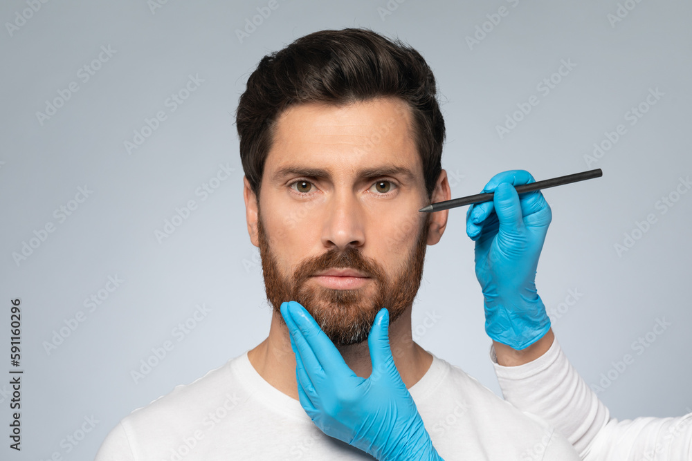 Middle aged man getting marks on face for cosmetic surgery, plastic surgeon applying marks on