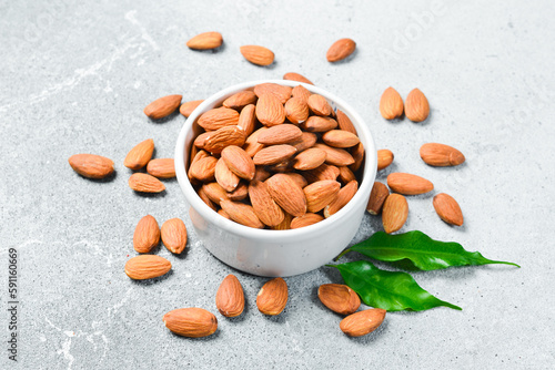White ceramic bowl with almonds on rustic table. Healthy snacks. Nuts