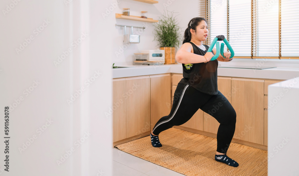 fat woman using fitness device exercising in kitchen. overweight woman training with flexing equipment follow home fitness trend. chubby asian woman workout in kitchen using fitness tool for muscle fat woman using fitness device exercising in kitchen. overweight woman training with flexing equipment follow home fitness trend. chubby asian woman workout in kitchen using fitness tool for muscle