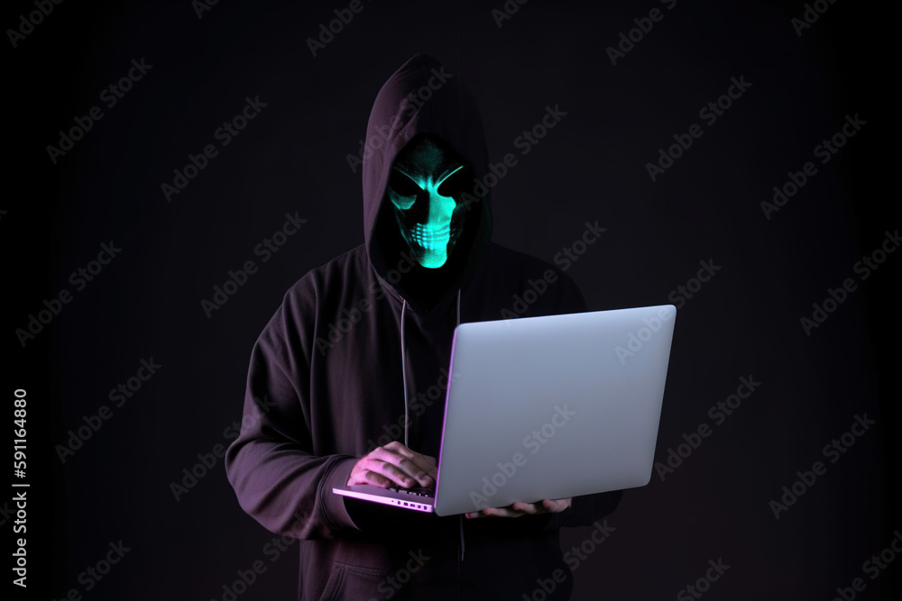 a hacker in a hoodie using a laptop computer isolated on dark background with neon light. Created with Generative AI Technology a hacker in a hoodie using a laptop computer isolated on dark background with neon light. Created with Generative AI Technology