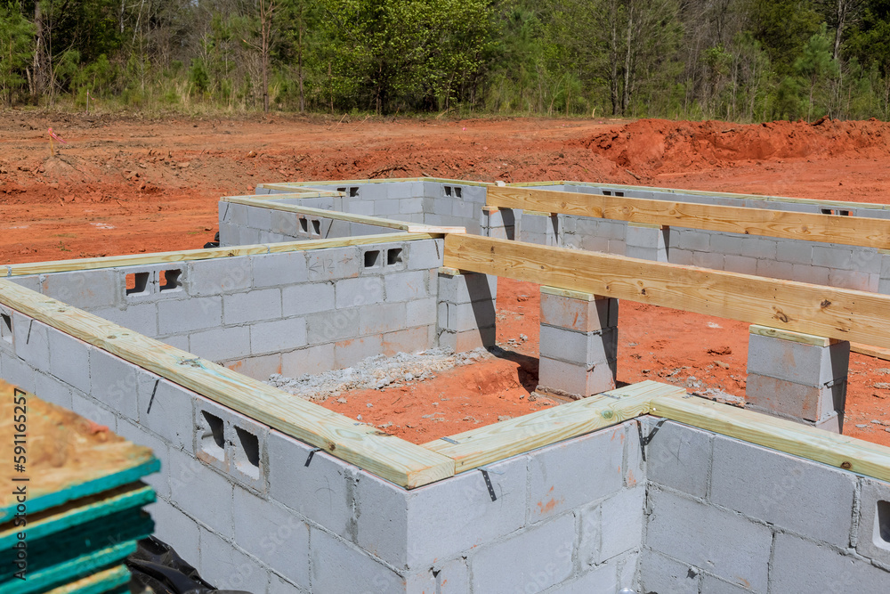 Construction site with cement blocks that will be used for walls holding up house foundation.