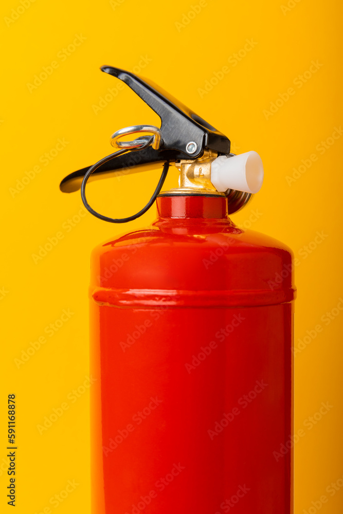 Fire extinguisher on a yellow background with place for text. Close-up. Fire extinguisher on the wall. Fire safety system. Security concept. Place for text. Copy space.