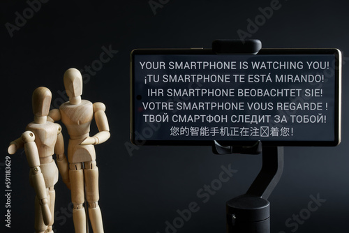 Human mannequins and a mobile phone with the words "your smartphone is watching you" in different languages. Concept of surveillance using a smartphone and viruses. Big Brother.