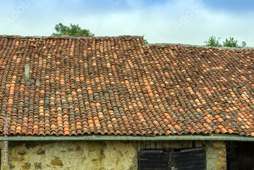 Fragment of an old stone farm barn with roof tiles